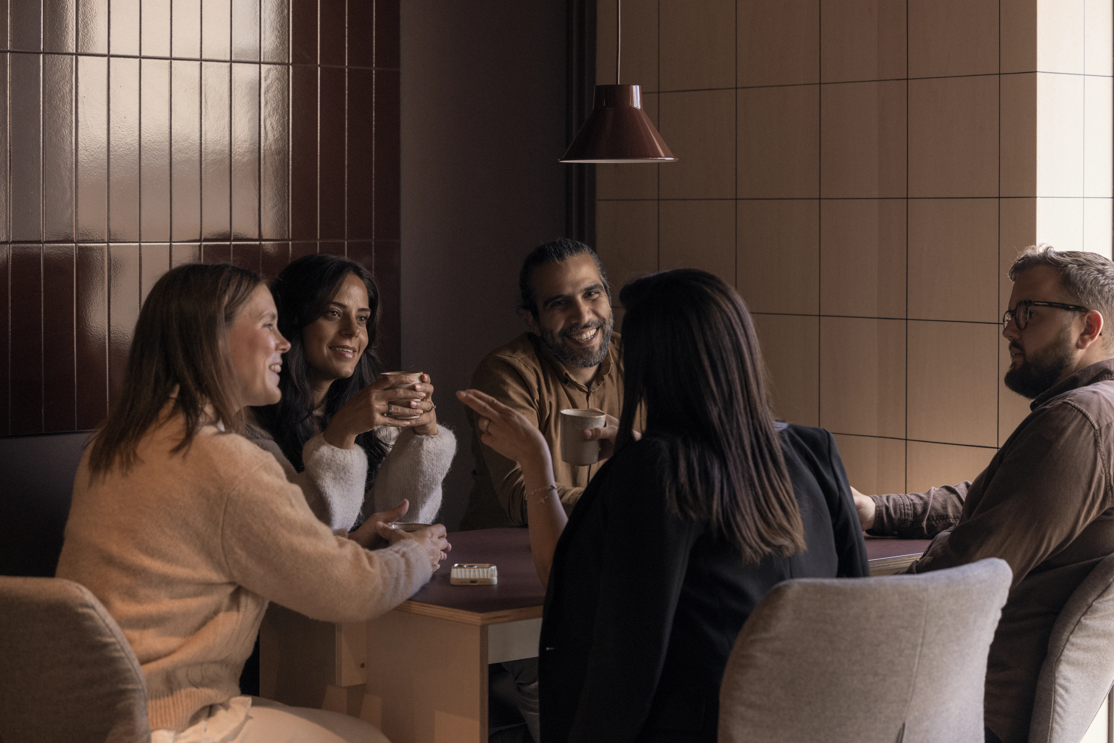 Fünf Kolleginnen und Kollegen im Gespräch in einer Lounge-Ecke.