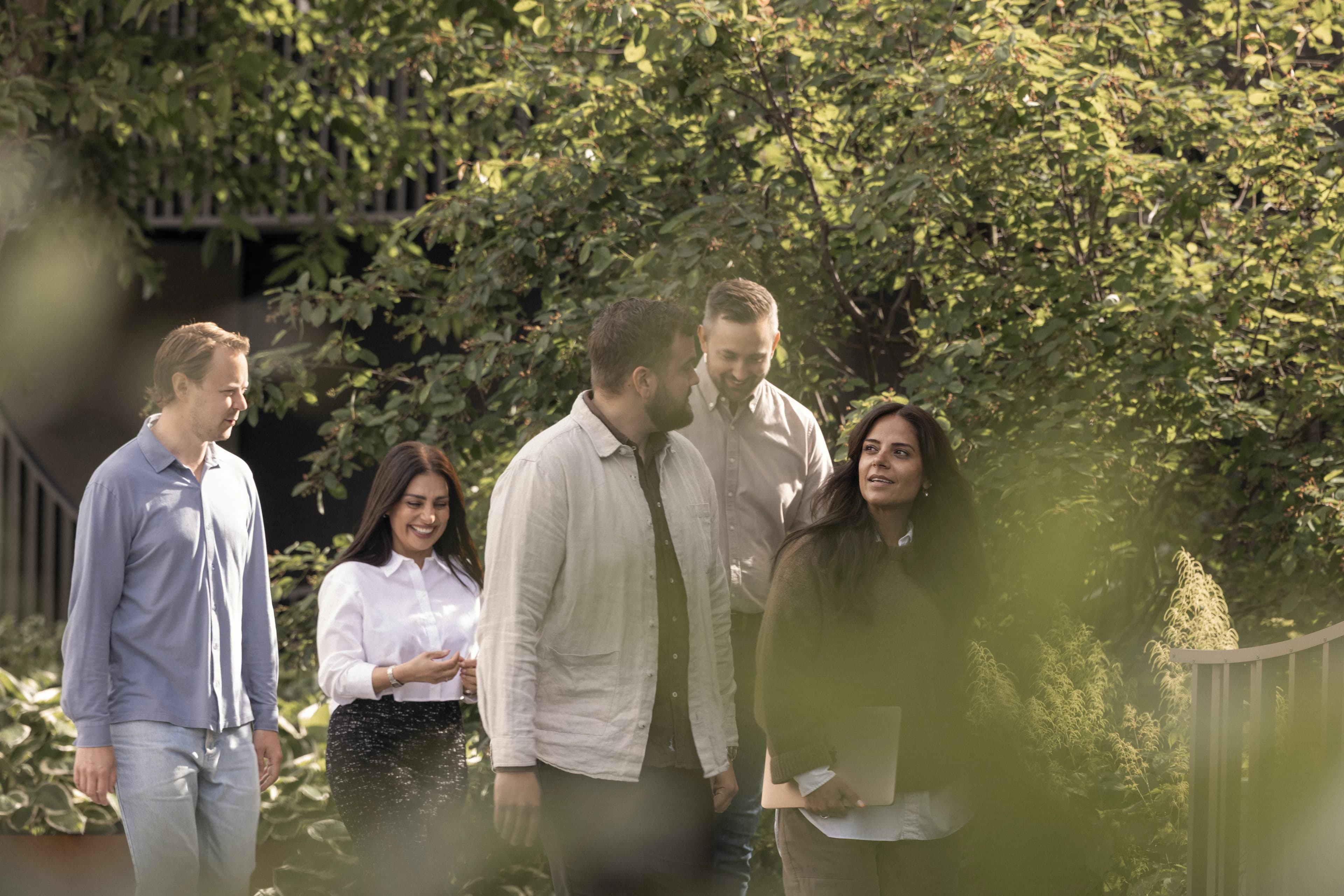 Group talking outdoors among trees.