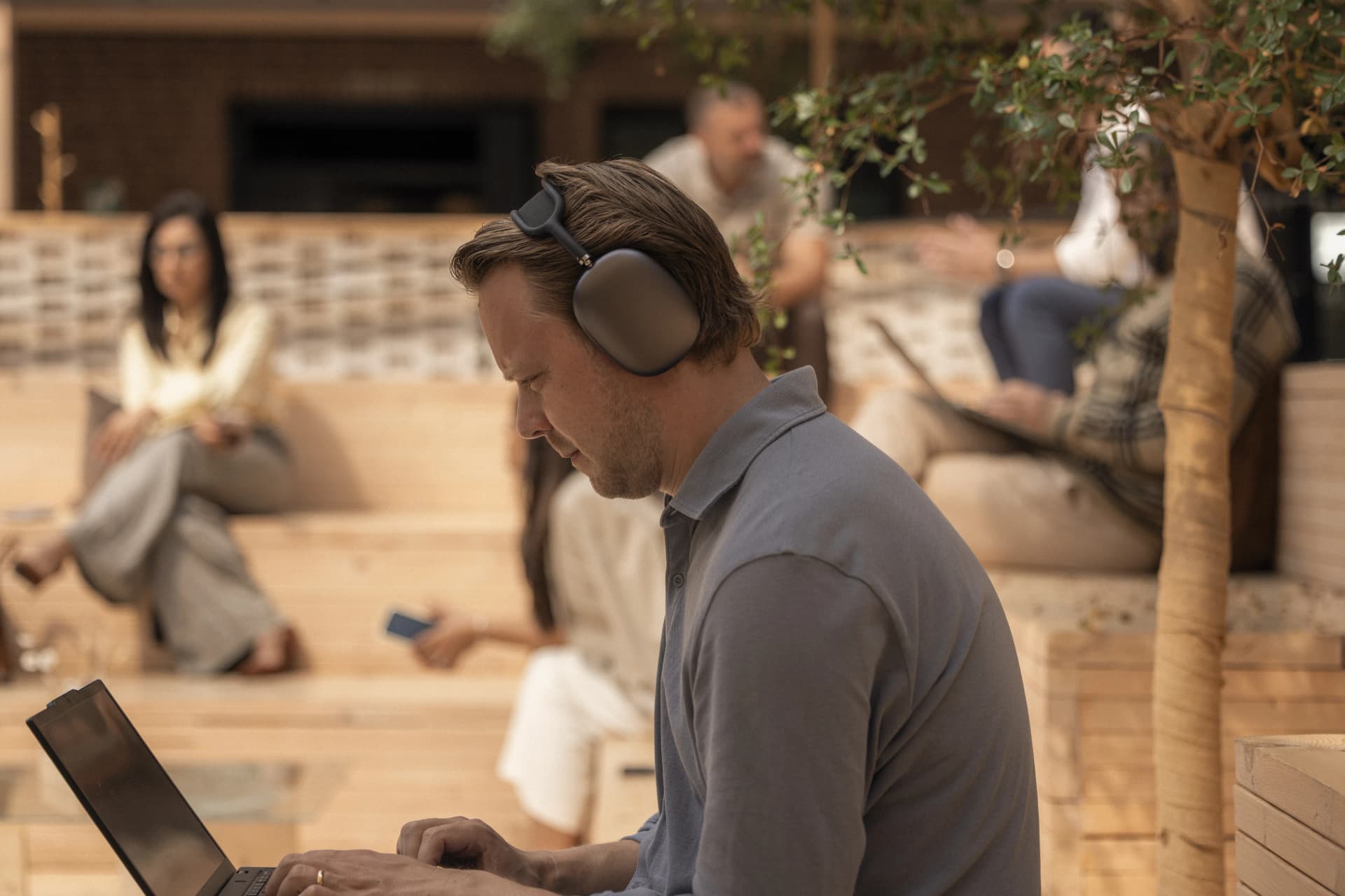 Man with headphones and a laptop in a lounge.