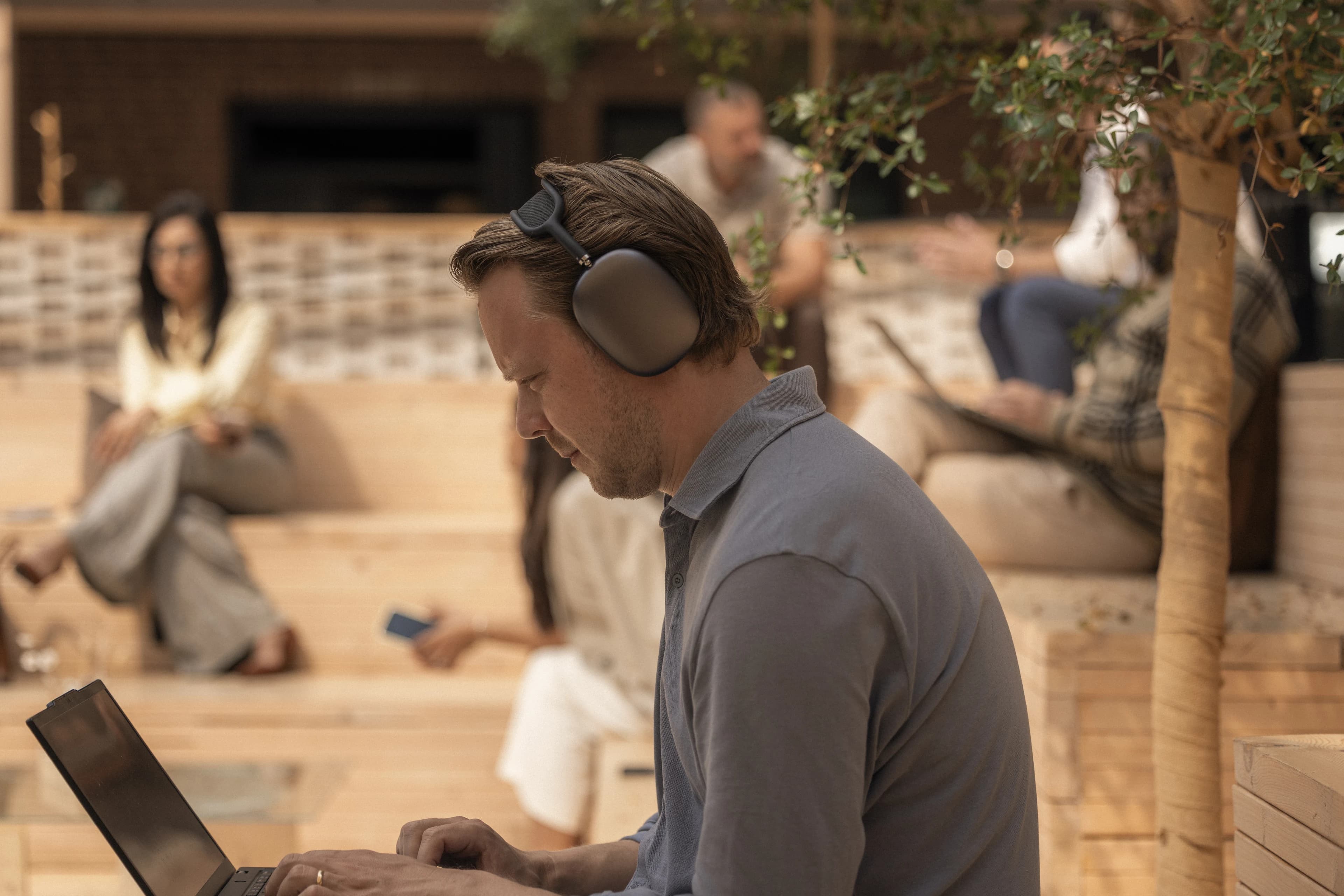 Man with headphones and a laptop in a lounge.